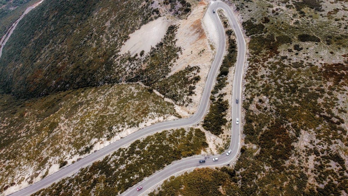 Captivating aerial shot of a winding road through autumn landscapes on a mountain.